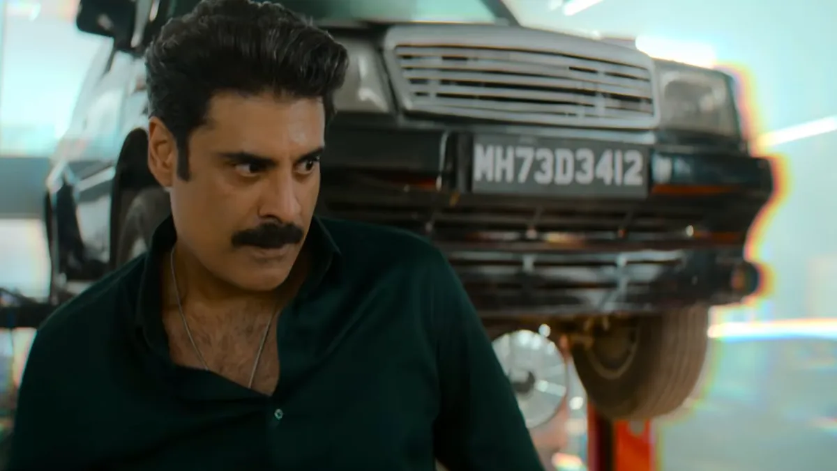 Sikandar Kher as Imtiaz Engineer in a garage, in front of a car raised on a lift