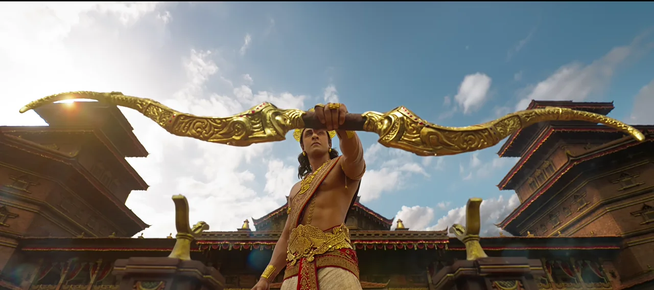 Ranbir Kapoor as Rama holding a giant golden bow above his head in front of a palace
